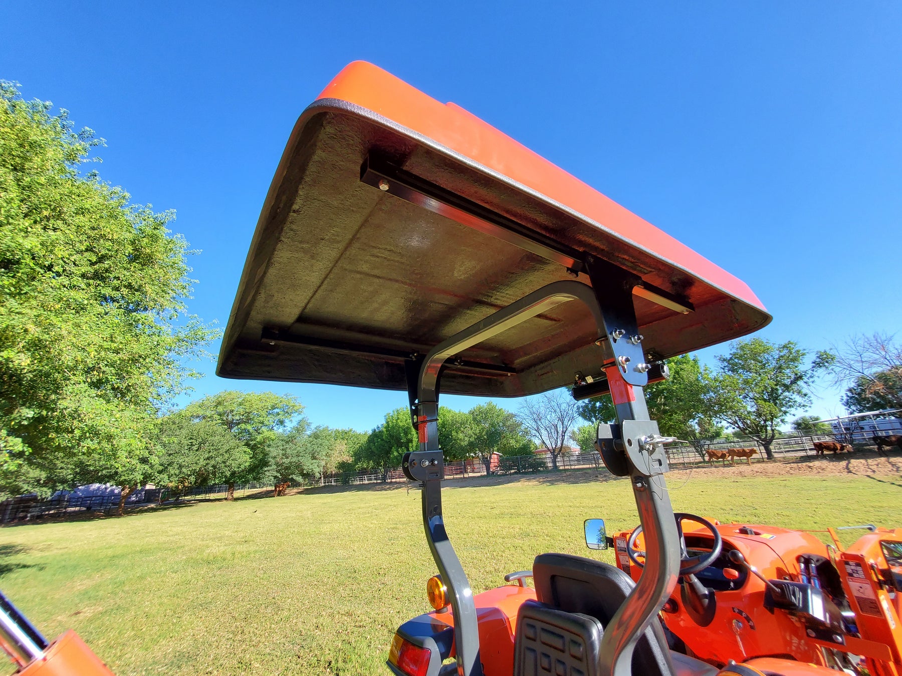 Underside view of an orange Tractor Sunshade R-Series canopy installed on a Kubota L2501, showing the adjustable Sliding Tube Kit and mounting hardware.