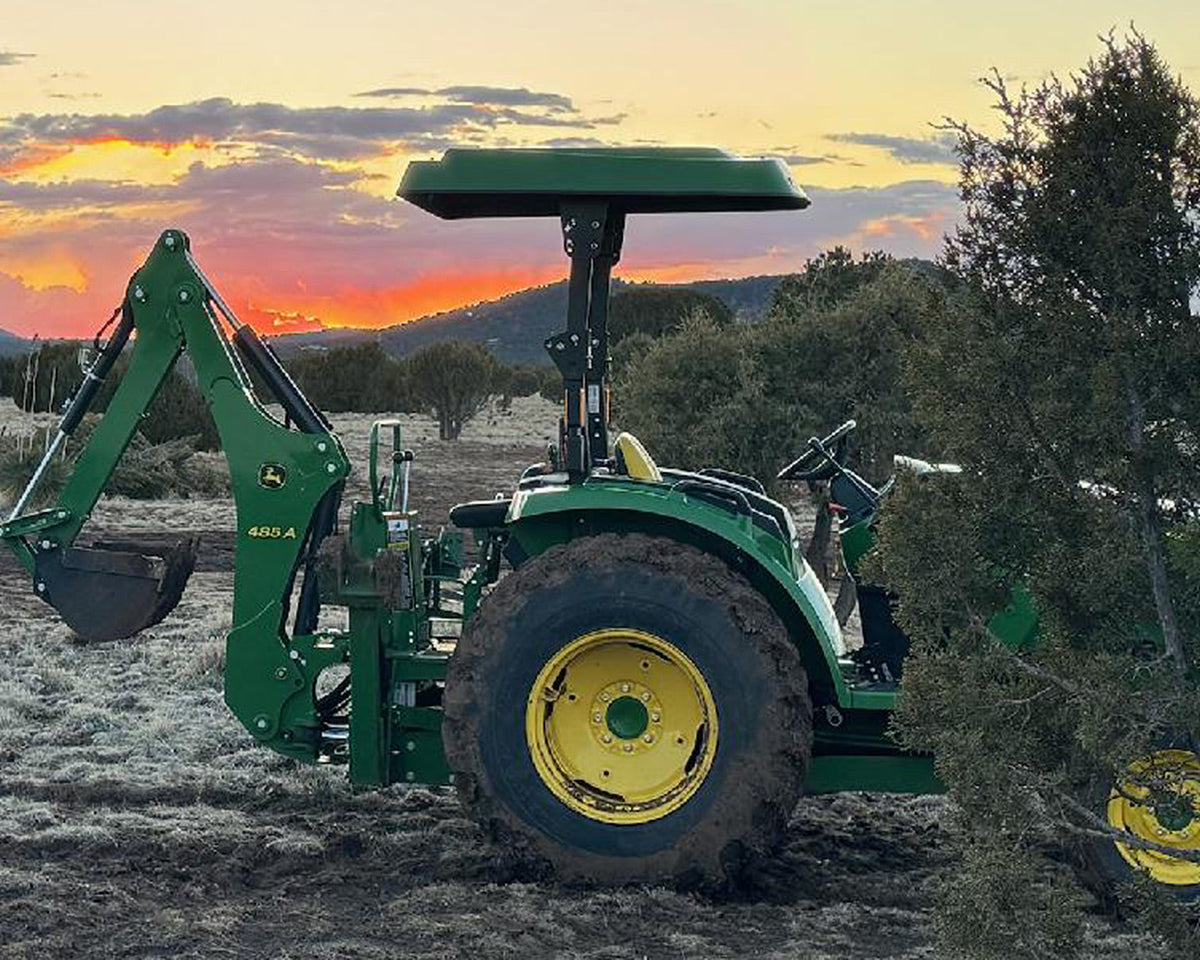 John Deere tractor equipped with a green Tractor Sunshade R1 canopy and adjustable Sliding Tube Kit at sunset.