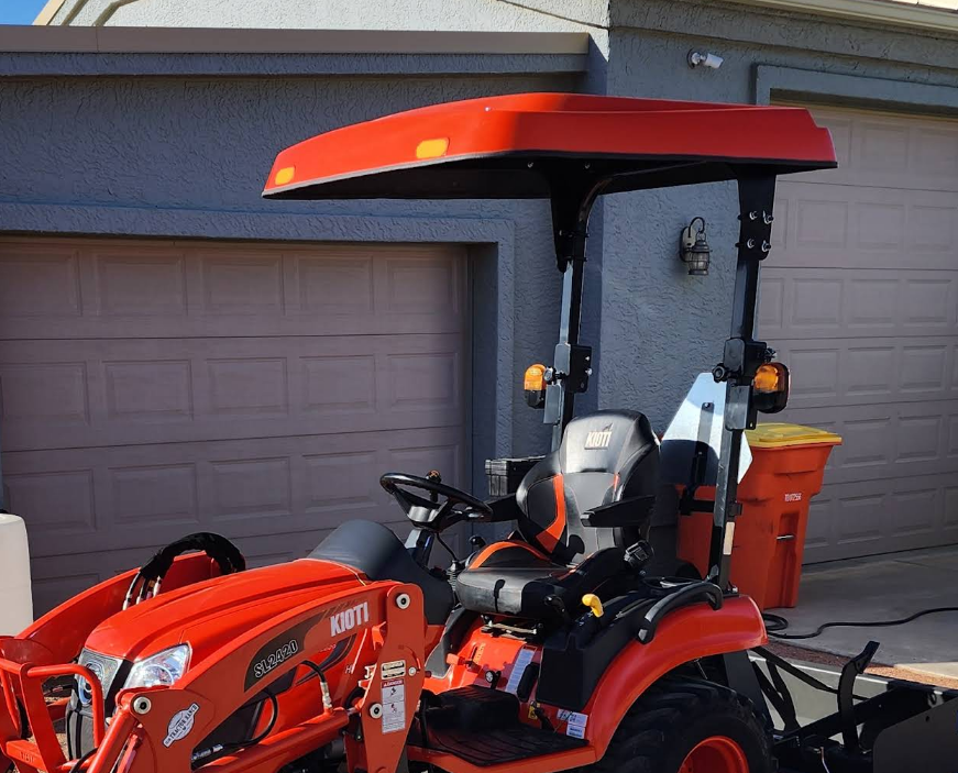 Orange KIOTI tractor equipped with a matching Tractor Sunshade R-Series fiberglass canopy.