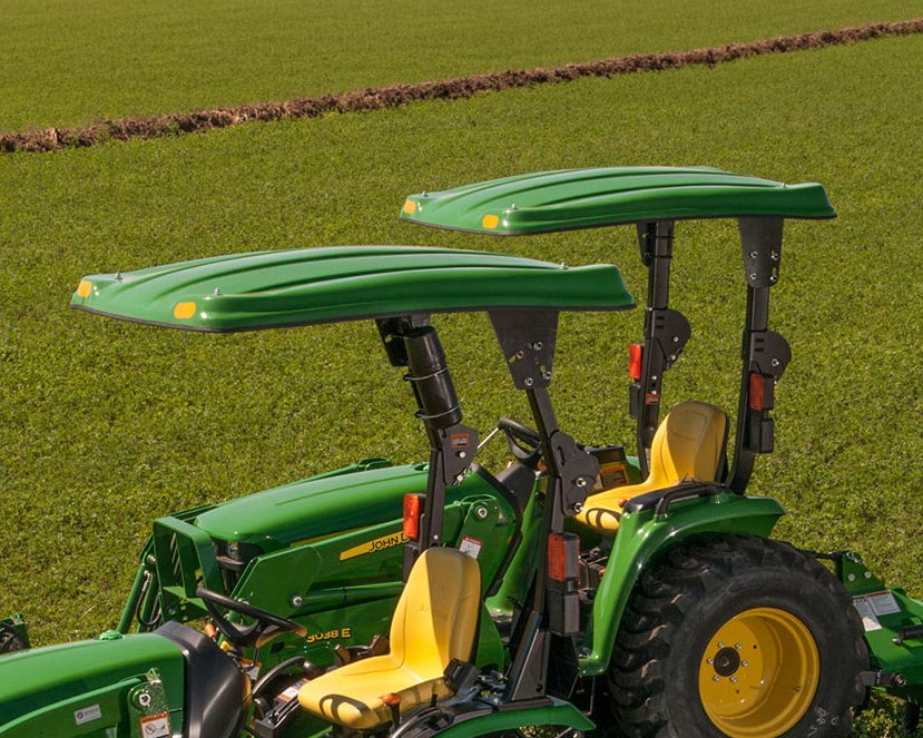 Two John Deere utility tractors fitted with green Tractor Sunshade N1 N-Series canopies in a field.