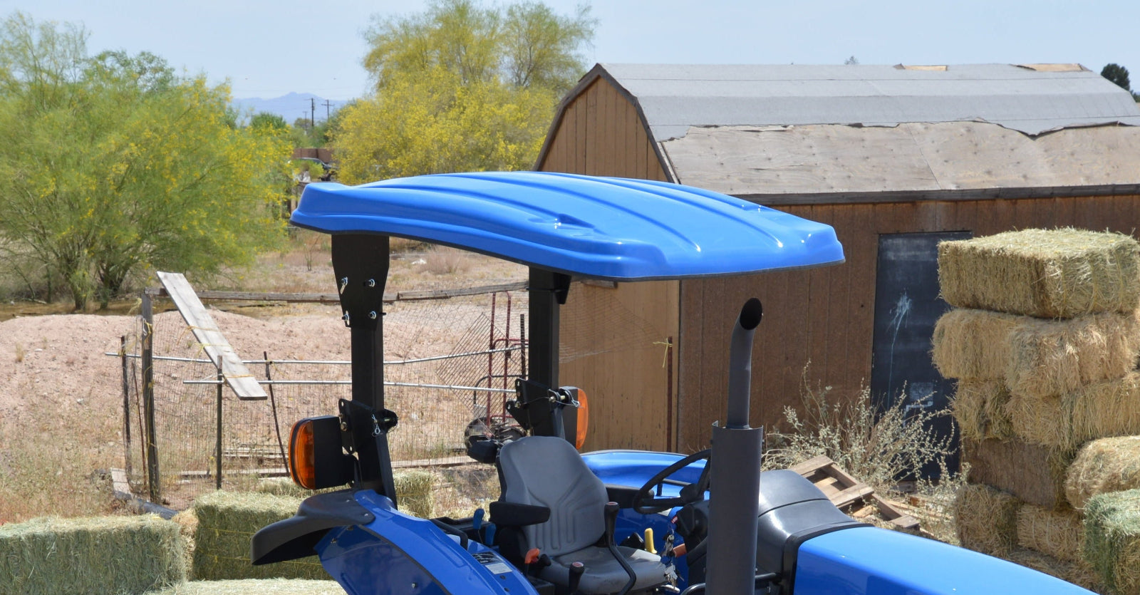 Blue New Holland tractor equipped with a Tractor Sunshade fiberglass canopy.